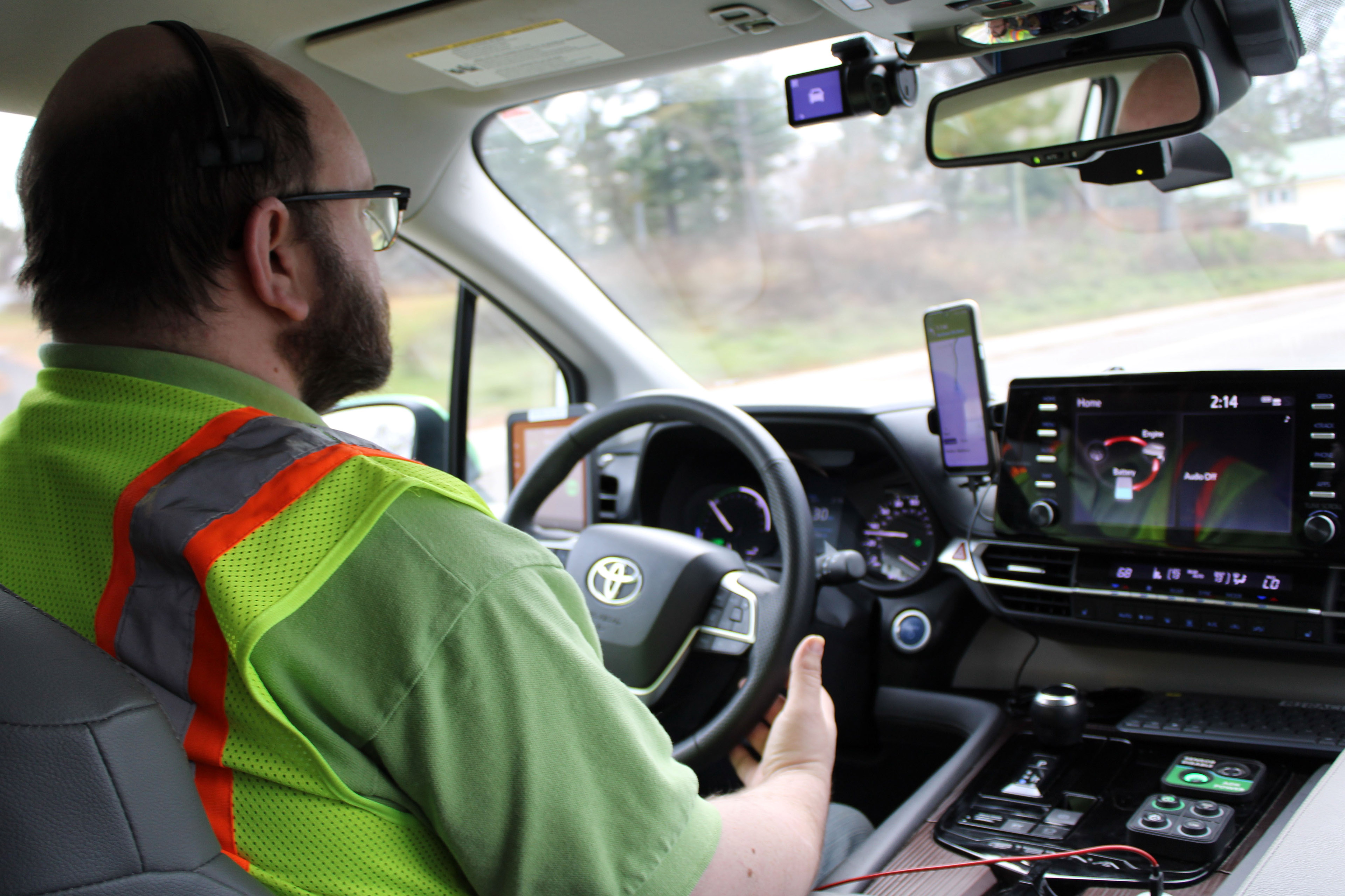 Operator Mark Haase sits in the driver's seat of the goMARTI self-driving vehicle. He keeps his hands cupped around the steering wheel as the van’s computer system drives.