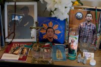 A collection of framed images, candles, a cross, a rosary, and other items on a table.